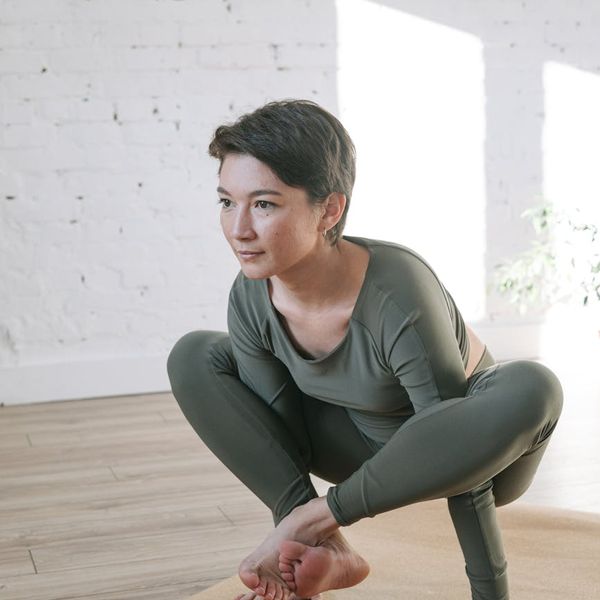 Woman in a calm yoga pose in a bright, serene room.