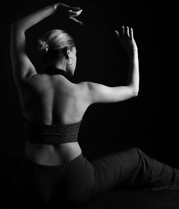 Woman performing a dynamic yoga stretch with a light blue background.